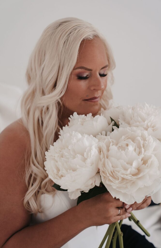 Hochzeitsplanerin Svenja Feddersen hält weiße Pfingstrosen im Arm – stimmungsvolles Porträt für Transparenz und Beratung.