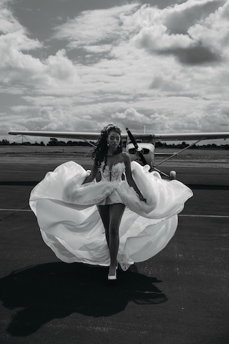 Braut in wehendem Kleid läuft über ein Flugfeld – dynamische Hochzeitsaufnahme.